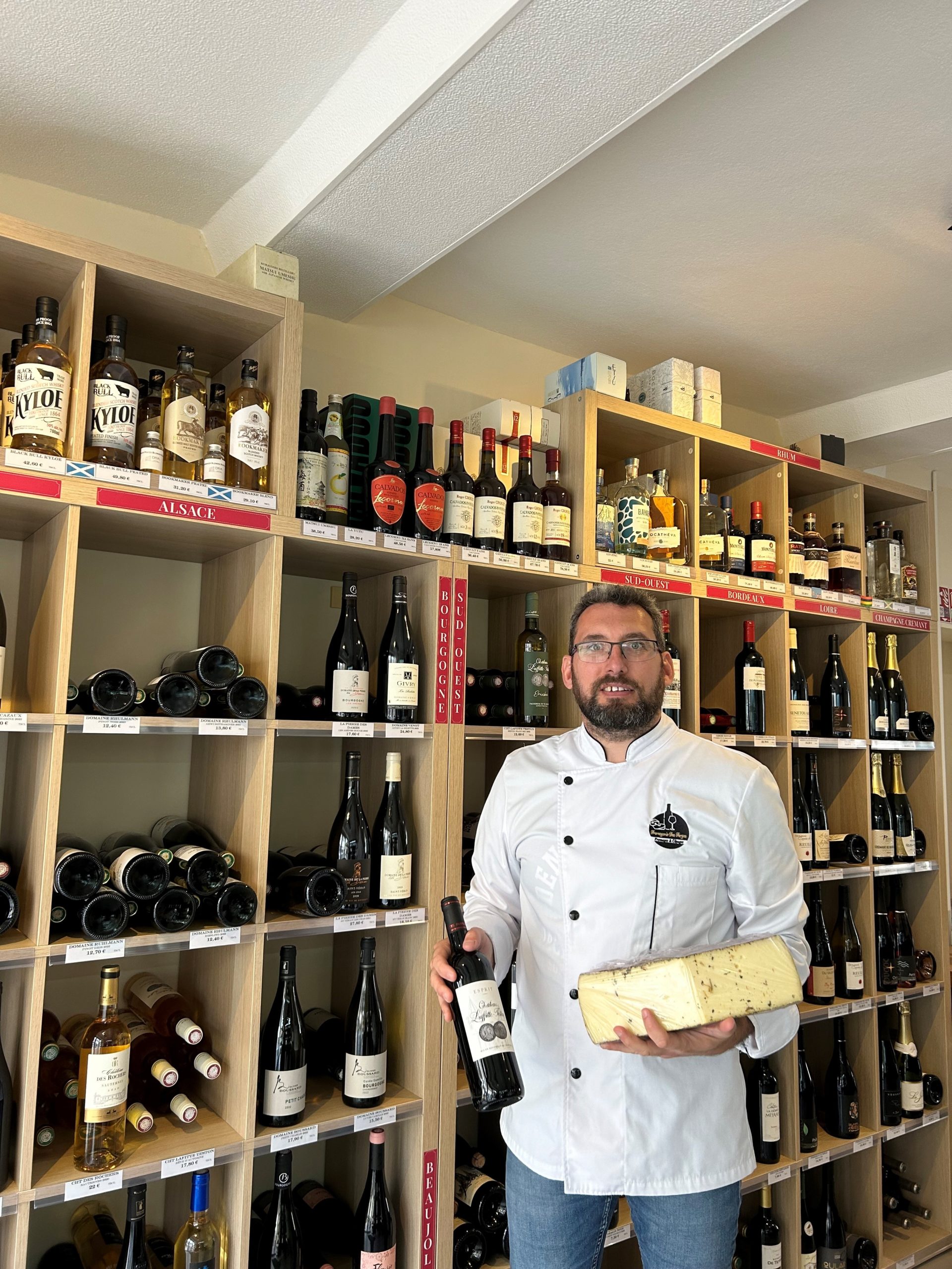 Fromager tenant un plateau de fromages et une bouteille de vin